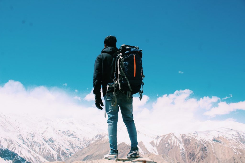 man with backpack standing on top of mountain