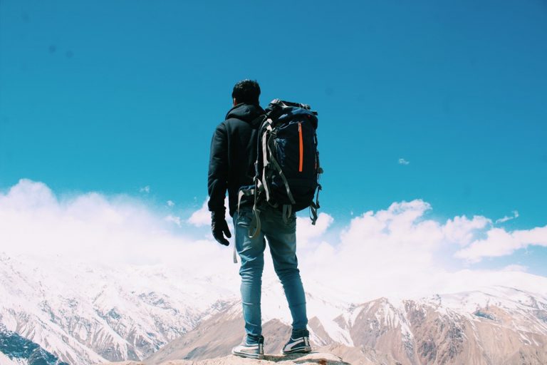 man with backpack standing on top of mountain
